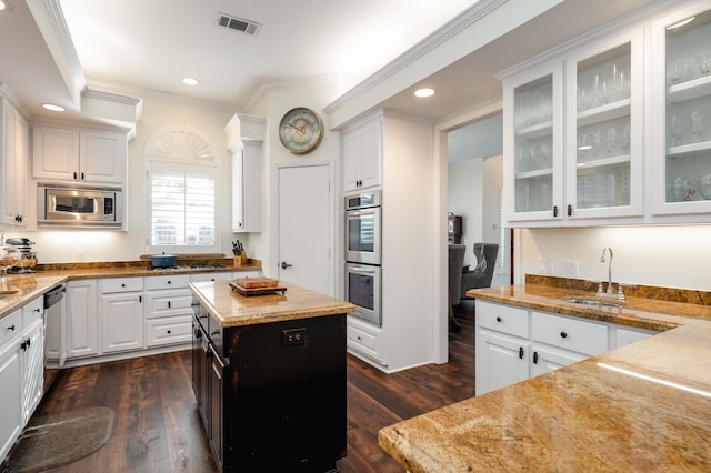 kitchen with white cabinetry, stainless steel appliances, light stone countertops, and dark wood-type flooring