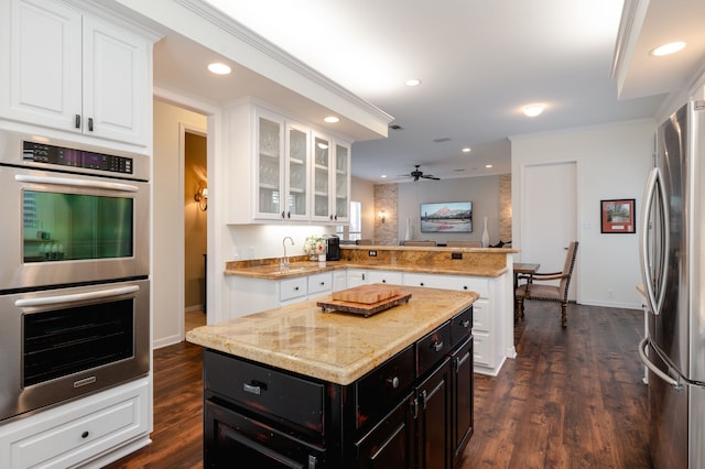 kitchen with white cabinetry, a center island, kitchen peninsula, and appliances with stainless steel finishes