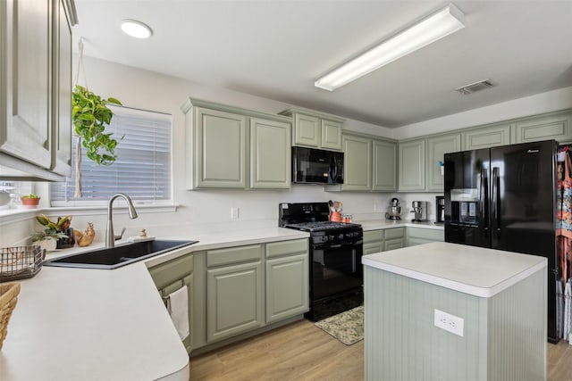 kitchen with black appliances, a kitchen island, light hardwood / wood-style floors, sink, and green cabinets