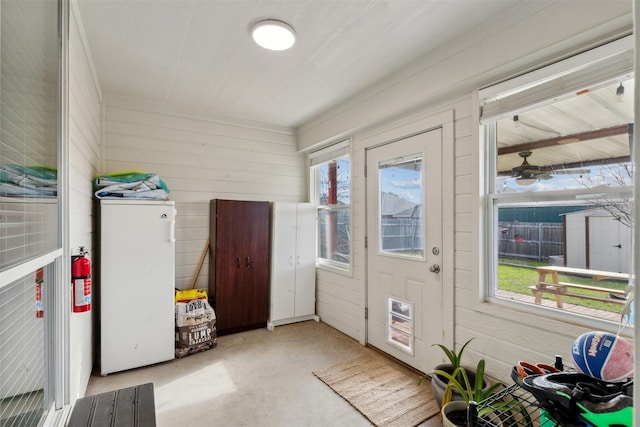 entryway with ceiling fan and wood walls