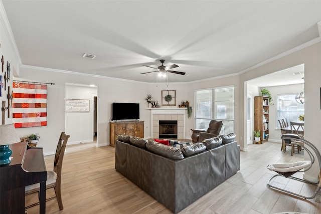 living room with a fireplace, light wood-type flooring, ceiling fan, and crown molding