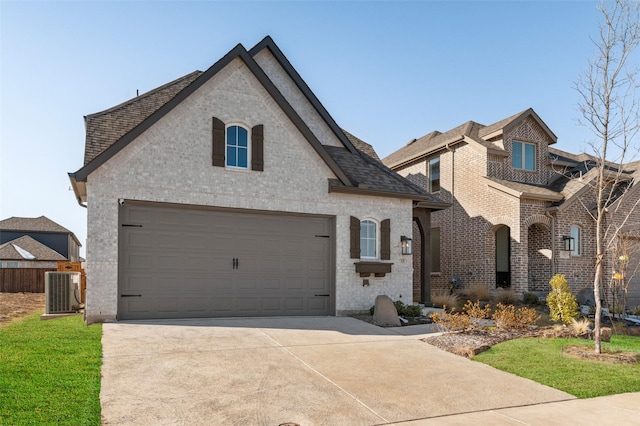 french provincial home featuring central air condition unit, brick siding, driveway, and a shingled roof