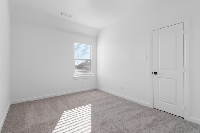 carpeted empty room featuring lofted ceiling