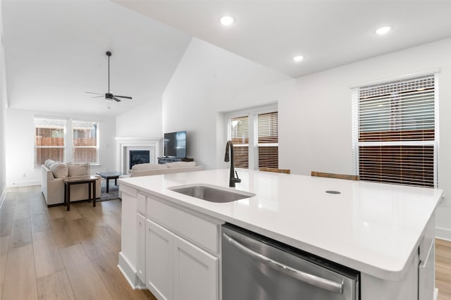 kitchen featuring sink, light hardwood / wood-style flooring, dishwasher, white cabinetry, and an island with sink