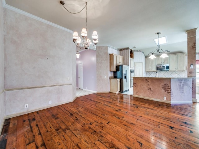 kitchen featuring tasteful backsplash, crown molding, an inviting chandelier, light wood-type flooring, and appliances with stainless steel finishes