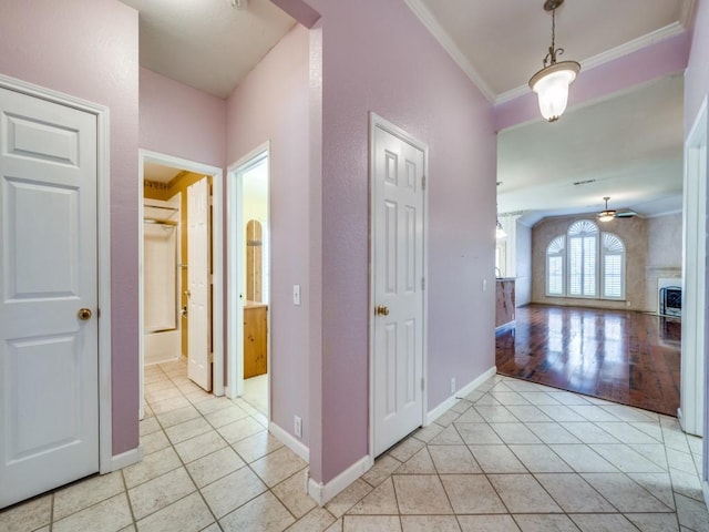 hall featuring light tile patterned floors and crown molding