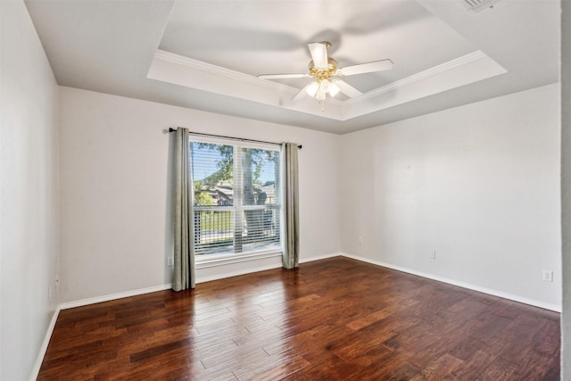 empty room with dark wood-type flooring, ceiling fan, a tray ceiling, and crown molding