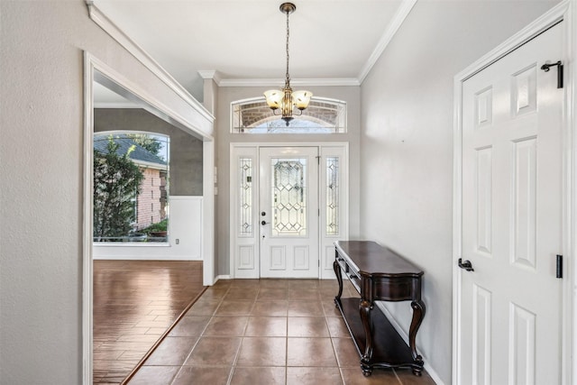 tiled entrance foyer featuring ornamental molding and an inviting chandelier