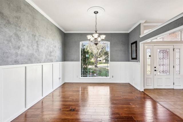 unfurnished dining area featuring ornamental molding, dark hardwood / wood-style floors, and a notable chandelier