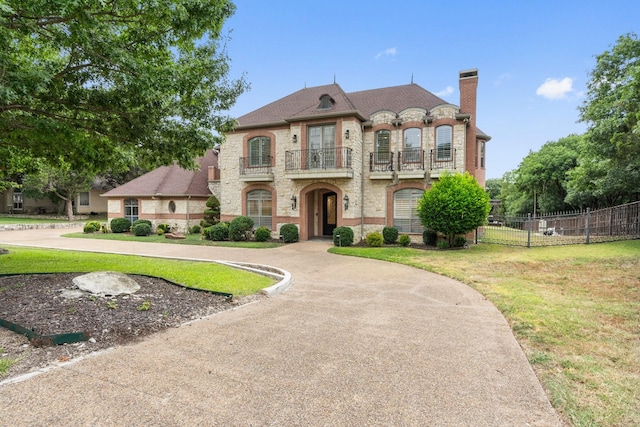 french country inspired facade with a balcony and a front lawn