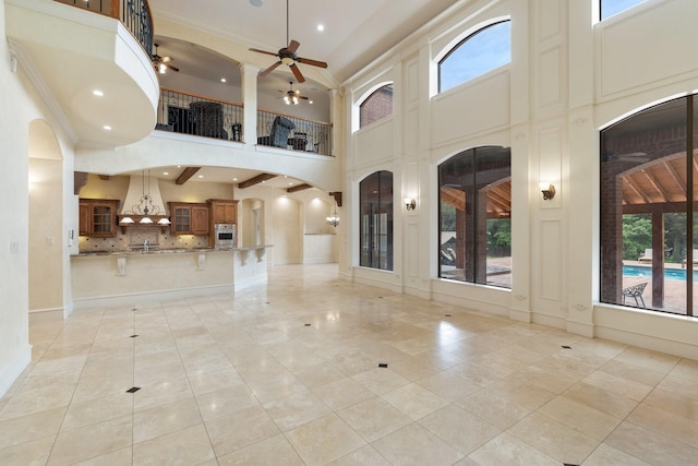 unfurnished living room featuring light tile patterned floors, a towering ceiling, and ceiling fan