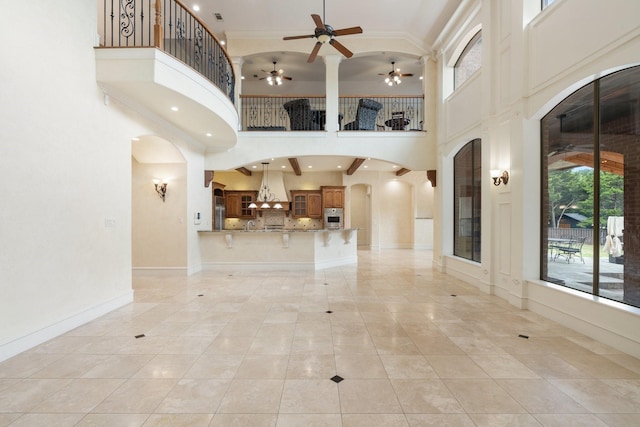 interior space with a high ceiling, light tile patterned floors, and ceiling fan