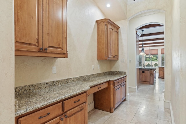 kitchen with beam ceiling, light stone countertops, and light tile patterned floors