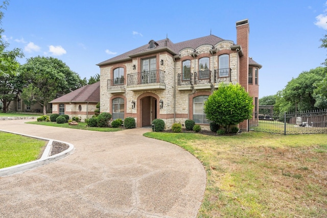 french provincial home featuring a balcony and a front lawn