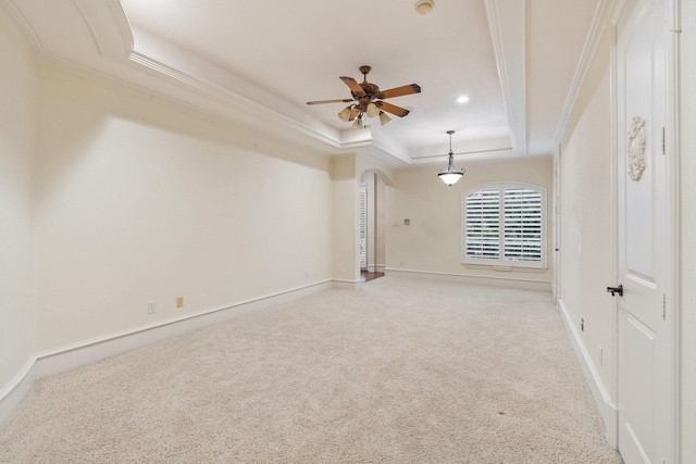 carpeted empty room featuring ceiling fan, crown molding, and a tray ceiling