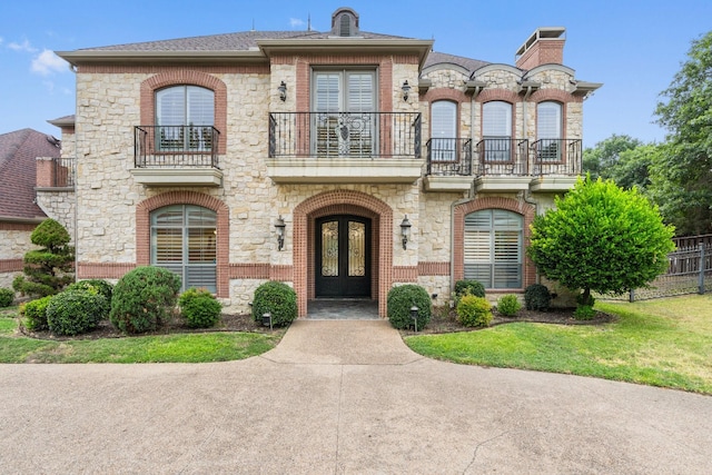 view of front of home featuring a front lawn, french doors, and a balcony