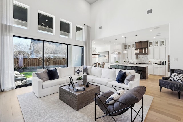 living room with sink, a high ceiling, and light wood-type flooring