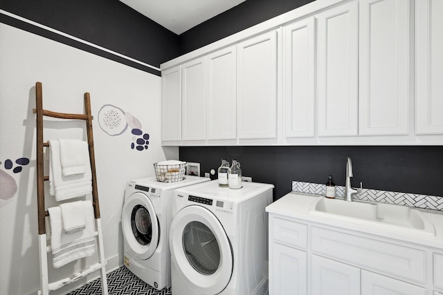 clothes washing area with washer and clothes dryer, cabinets, and sink