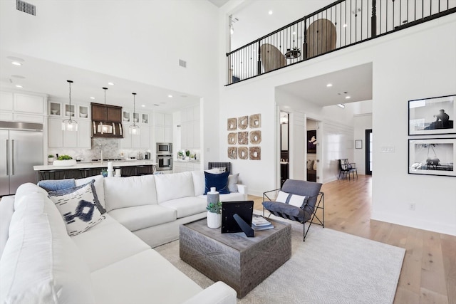 living room featuring light hardwood / wood-style floors and a towering ceiling