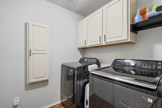 laundry area featuring cabinets, dark hardwood / wood-style flooring, and washing machine and clothes dryer