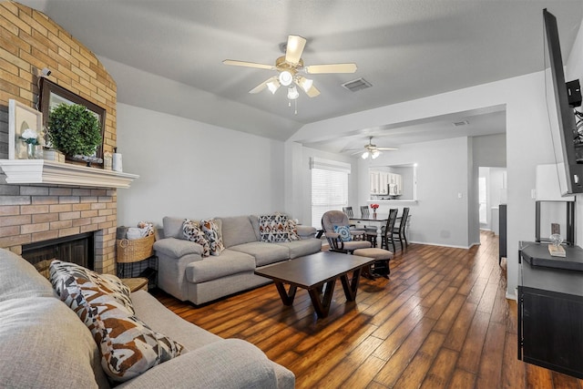 living room featuring a fireplace, lofted ceiling, ceiling fan, and dark wood-type flooring