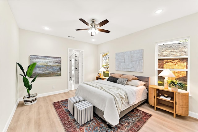 bedroom with ceiling fan, light hardwood / wood-style floors, and ensuite bath