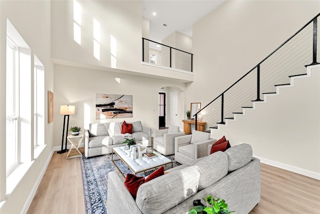 living room with a towering ceiling and light wood-type flooring