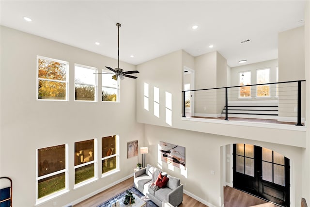 living room with wood-type flooring, french doors, ceiling fan, and a high ceiling