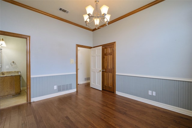 unfurnished room with a chandelier, dark hardwood / wood-style floors, and ornamental molding