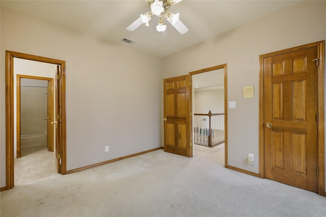 unfurnished bedroom featuring light colored carpet, ceiling fan, and ensuite bathroom