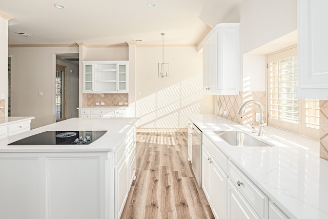 kitchen with white cabinetry, sink, light stone countertops, decorative light fixtures, and black electric cooktop