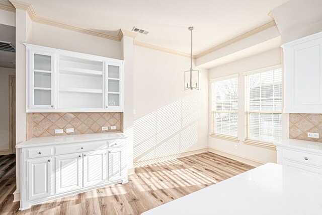 kitchen with white cabinets, hanging light fixtures, light hardwood / wood-style flooring, decorative backsplash, and a notable chandelier