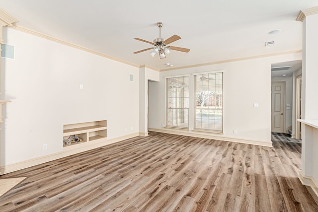 unfurnished living room with built in shelves, ceiling fan, and ornamental molding