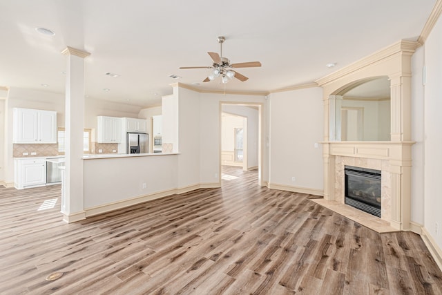 unfurnished living room featuring ceiling fan, light hardwood / wood-style floors, crown molding, and a fireplace