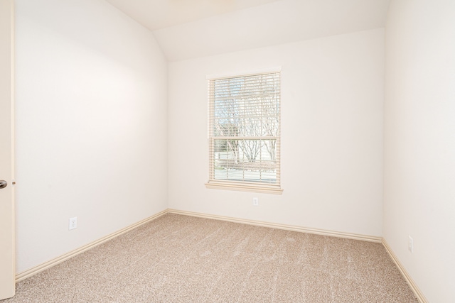 spare room featuring carpet flooring and lofted ceiling