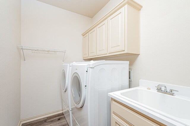 laundry room featuring separate washer and dryer, sink, cabinets, and light hardwood / wood-style floors