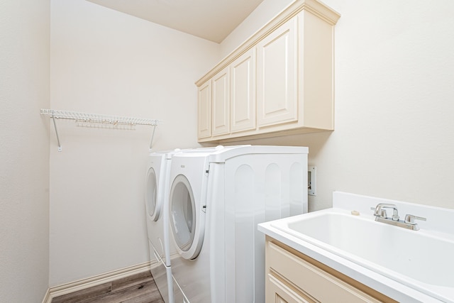 laundry room featuring washer and dryer, sink, light hardwood / wood-style floors, and cabinets