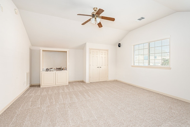 unfurnished bedroom featuring a closet, light colored carpet, ceiling fan, and lofted ceiling