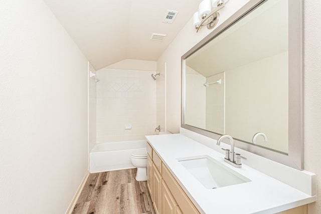 full bathroom with vanity, hardwood / wood-style floors, toilet, tiled shower / bath, and lofted ceiling