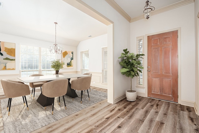 dining space featuring vaulted ceiling, an inviting chandelier, light hardwood / wood-style flooring, and ornamental molding