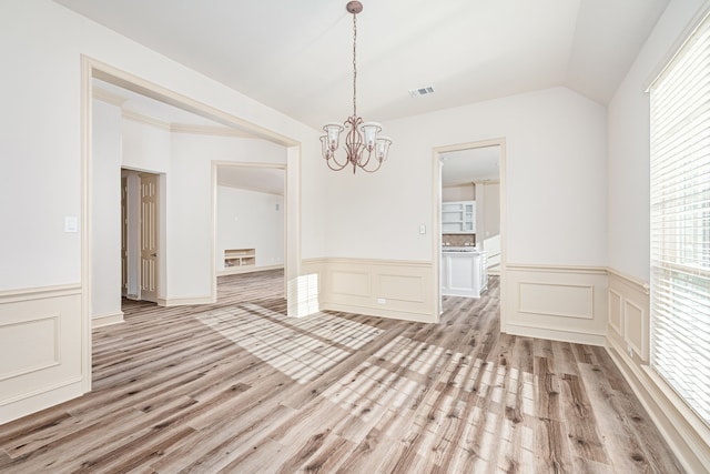 unfurnished dining area with light hardwood / wood-style floors, lofted ceiling, and a notable chandelier