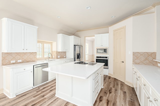 kitchen with decorative backsplash, white cabinetry, stainless steel appliances, and a kitchen island with sink