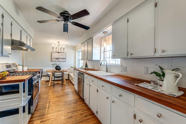 kitchen featuring white cabinetry, sink, stainless steel appliances, wooden counters, and pendant lighting