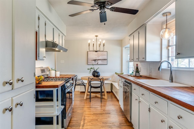 kitchen featuring butcher block counters, sink, hanging light fixtures, appliances with stainless steel finishes, and white cabinetry