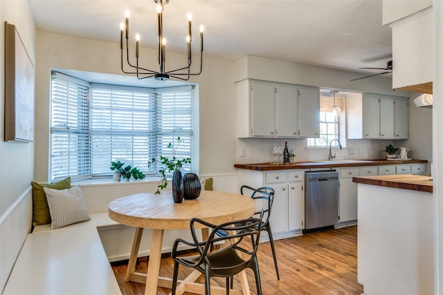 kitchen with white cabinets, ceiling fan with notable chandelier, stainless steel dishwasher, tasteful backsplash, and butcher block counters