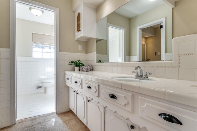 bathroom with vanity, tile walls, and toilet