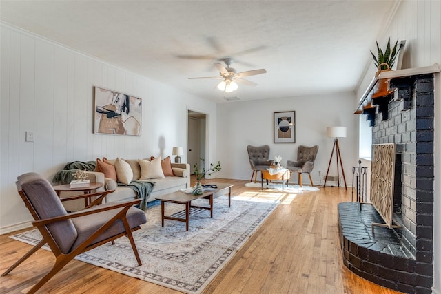 living room featuring ceiling fan, light hardwood / wood-style floors, and a fireplace