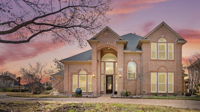 view of front of home featuring brick siding and a shingled roof