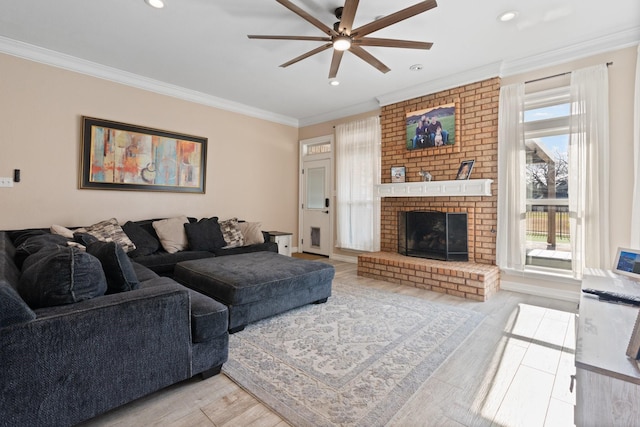 living room with light hardwood / wood-style floors, ceiling fan, a brick fireplace, and ornamental molding