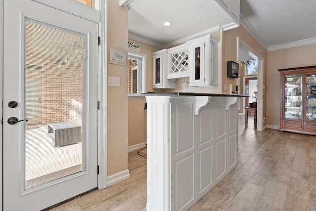 kitchen featuring white cabinets, crown molding, a kitchen breakfast bar, and light hardwood / wood-style flooring